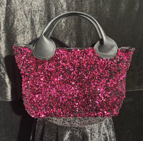 Pink-schwarze Paillettentasche mit schwarzen Griffen, intensiv funkelnd.