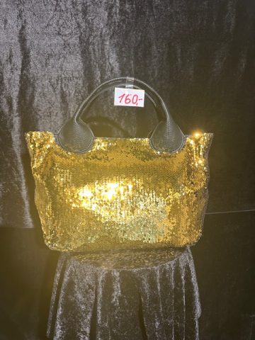 Goldene Paillettentasche mit schwarzen Griffen vor dunklem Hintergrund.
